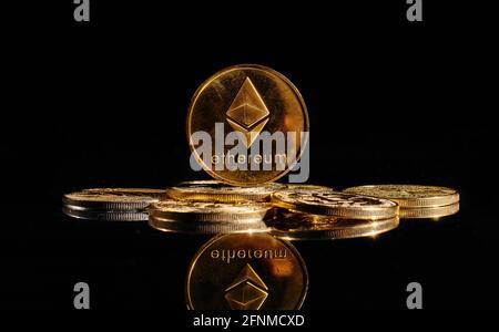 Nahaufnahme Goldmünze mit Äther-Logo. Neue Kryptowährung Ethereum ETH 2.0 auf einer Spitze von Bitcoin-Münzen vor schwarzem Hintergrund. Ein Haufen dezentraler Stockfoto