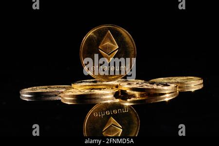 Nahaufnahme Goldmünze mit Äther-Logo. Neue Kryptowährung Ethereum ETH 2.0 auf einer Spitze von Bitcoin-Münzen vor schwarzem Hintergrund. Ein Haufen dezentraler Stockfoto