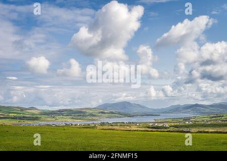 Blick von den Kerry Cliffs auf das Dorf Portmagee, Felder und Bauernhöfe mit Fjord und Bergkette im Hintergrund, Halbinsel Iveragh, Ring of Kerry, Irland Stockfoto