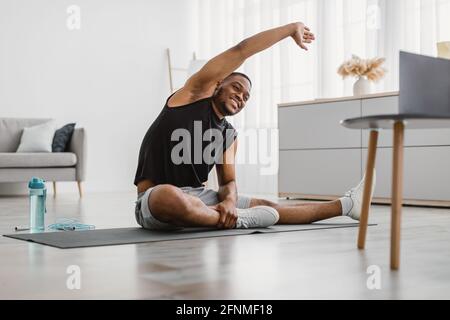 Fröhlicher Schwarzer Mann Macht Side Bend Stretching-Übung Zu Hause Stockfoto