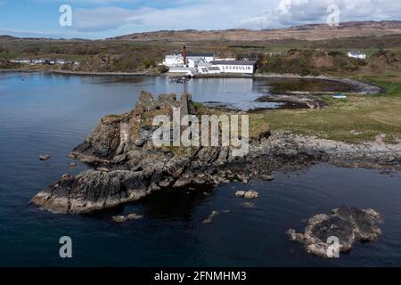 Dunyvaig Burgruine mit Blick auf die Lagavulin Distillery, Lagavulin Bay, Islay, Schottland. Lagavulin ist eine Destillerie, die sich im Besitz von Diageo befindet. Stockfoto