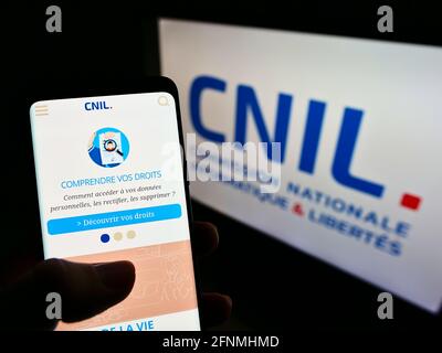 Person mit Mobiltelefon und Webseite der nationalen französischen Datenschutzbehörde CNIL auf dem Bildschirm mit Logo. Konzentrieren Sie sich auf die Mitte des Telefondisplays. Stockfoto