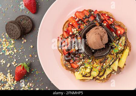 Herzwaffel mit Ananas und Erdbeere mit Gummy Candy und Eis darauf. Stockfoto