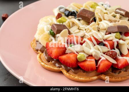 Herzwaffel mit Banane und Erdbeere mit Gummy Candy und Eis darauf. Stockfoto