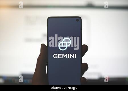 SWANSEA, Großbritannien - 2. MAI 2021: Mann mit Smartphone und Gemini App-Logo mit verschwommenem Website-Hintergrund. Kryptowährungsbörse, Wallet-Plattform Stockfoto