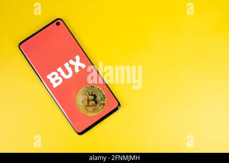 SWANSEA, UK - 4. MAI 2021: Smartphone mit Bux-Logo mit Bitcoin-Münze auf gelbem Hintergrund. Mobile Investing App, Brokerage-Unternehmen in Europa Stockfoto