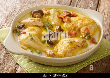 Coq au Riesling Hähncheneintopf in cremiger Weinsauce, Speck und Pilze aus der Nähe in einem Topf auf dem Tisch. Horizontal Stockfoto