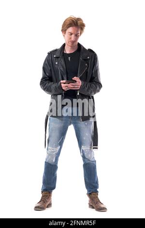 Cool entspannt stilvolle Rocker in Lederjacke mit Telefon und grinsen. Ganzkörperlänge isoliert auf weißem Hintergrund Stockfoto