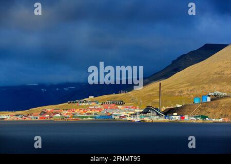 Longyearbyen, größte Siedlung und Verwaltungszentrum von Svalbard, Norwegen. Dunkler Wolkenabend mit wunderschönem Sonnenuntergangslicht. Stadt in der Natur Stockfoto