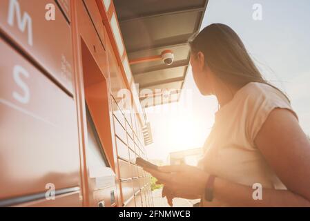 Frau holt Post vom automatischen Post-Terminal-Automaten ab. Stockfoto