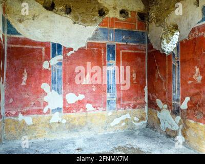 Das Zimmer ist im vierten Stil mit roten Paneelen auf einem dunkelblauen Boden über einem unteren roten Fries eingerichtet. Auf den Tafeln sind kleine Kameen von Soldaten in verschiedenen Positionen zu sehen. Haus des Octavius Quartio - Pompeji archäologische Stätte, Italien Stockfoto