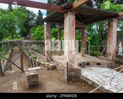 In der Mitte der oberen Pergola befindet sich ein kleiner Tetrastyle-Tempel, der über einem Nymphäum errichtet wurde, das Diana und Actaeon gewidmet ist. Das Nymphäum speiste einen langen Kanal, der mitten durch den großen Garten lief, der sich auf einer niedrigeren Ebene als das Haus selbst befand. Der Kanal wurde mit Brunnen, Statuen und Reliefs verziert - Haus des Octavius Quartio - Pompeji archäologische Stätte, Italien Stockfoto