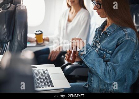Frau in Denim Jacke öffnen Tomatensaftflasche Stockfoto