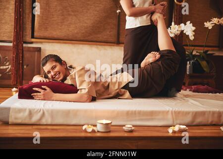 Lachende Dame mit Fußmassage von Thai-Spezialist Stockfoto