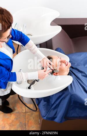 Weibliche coiffeur waschen Männer Haare Friseur Stockfoto