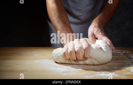 Baker's Hände machen den Teig für Brot oder Pizza auf Holzteig Brett. Nahaufnahme, Platz für Text. Stockfoto