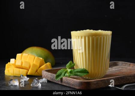 Kurkuma lassie oder Mango Lassi auf schwarzem Hintergrund mit Kopierfläche. Traditionelles indisches kaltes Getränk mit Mango. Frische Lassi aus Joghurt, Wasser, s Stockfoto