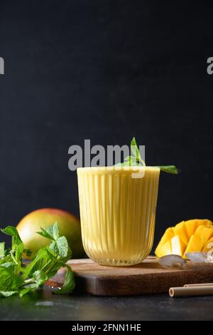 Indische ayurvedische Mango lassie oder Lassi auf schwarzem Hintergrund. Vertikales Format. Traditionelles gesundes Getränk mit Mango. Frische Lassi aus Joghurt, wat Stockfoto