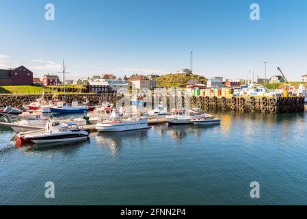 Traditionelles Hafendorf im Norden islands an einem sonnigen Sommermorgen. Boote, die an den Anlegestellen festgemacht sind, befinden sich im Vordergrund. Stockfoto