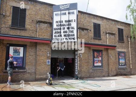 London, Großbritannien, 18. Mai 2021: Mitarbeiter der Clapham-Niederlassung der Kinokette Picturehaus reinigen Fassade und Eingangshalle, um sich auf die morgige Wiedereröffnung vorzubereiten. Das Kino ist seit dem 8. Oktober 2020 wegen der Coronavirus-Pandemie geschlossen. Anna Watson/Alamy Live News London, Großbritannien, 18. Mai 2021: Das V&A Museum wird morgen mit der Ausstellung „Alice: Curiouser and Curiouser“ wieder eröffnet, in der alle Aspekte des Kultkindbuches, seine Schöpferin, seine Muse und sein langes Vermächtnis in Film, Mode und Kunst erkundet werden. Anna Watson/Aamy Live News. Stockfoto