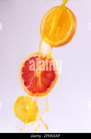 Gießen Sie frischen Zitronensaft über die Scheiben von Grapefruit, Orange und Zitrone Stockfoto