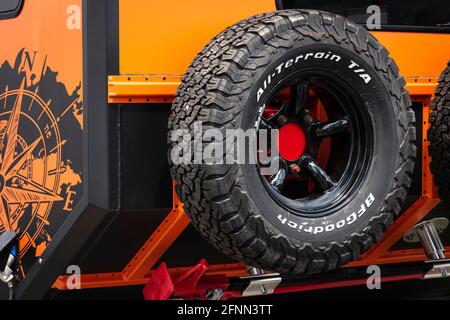 Camping und Wohnwagen. BF Goodrich All-Terrain T/A-Reifen hinten an einem orangefarbenen Land Rover Defender 4X4 Lkw befestigt. Stockfoto