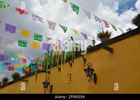 Typische elegante ockerfarbene façade aus der spanischen Kolonialzeit mit bunten, festlichen Papel picado-Bannern in San Miguel de Allende Mexiko Stockfoto