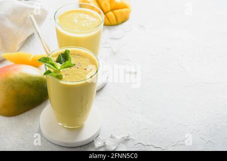 Indische gesunde ayurvedische Mango-Lassi auf grauem Hintergrund mit Kopierraum. Nahaufnahme. Frische Mangolassi aus Joghurt, Wasser, Gewürzen, Früchten und Eis Stockfoto