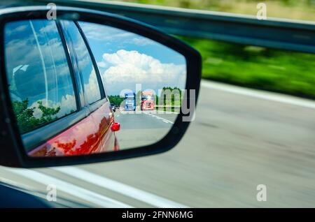Spiegelung zweier verschwommener Überholwagen im Rückspiegel Auf der Autobahn Stockfoto