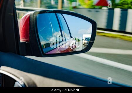 Spiegelung unscharfer Autos im Rückspiegel auf der Autobahn An einem schönen sonnigen Tag Stockfoto