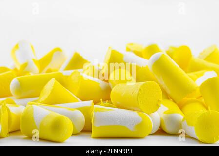 Makroaufnahmen von mehreren Ohrstöpseln in Gelb und Weiß zum Schutz vor Geräuschen, isoliert auf weißem Hintergrund. Stockfoto