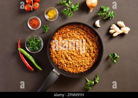 Keema Curry in Bratpfanne über dunklem Hintergrund. Indische und pakistanische Gerichte. Draufsicht, flach liegend, Nahaufnahme Stockfoto