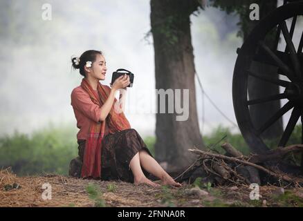 Thailändische Bäuerin in der lokalen thailändischen Tradition sitzt auf ihr Bauernhof und Büffel Hintergrund, Land Thailand Stockfoto