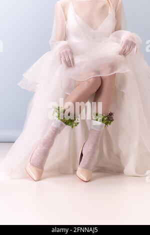 Nahaufnahme passen weibliche Beine mit Blumen und Pflanzen in Kunst-Aktion isoliert auf weißem Hintergrund. Retro-Stil, Vergleich von Epochen-Konzept. Stockfoto