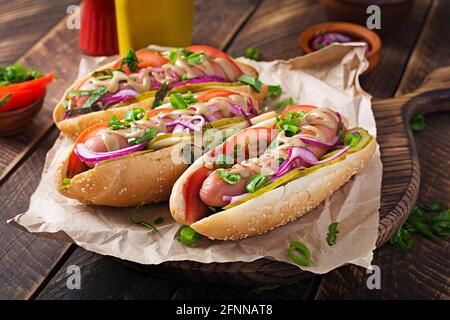 Hot Dog mit Gurken, Tomaten und Salat auf Holzboden. Hotdog, amerikanische Küche. Stockfoto