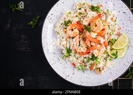 Couscous mit gerösteten Garnelen, Tomaten, roten Zwiebeln, Mandelnüssen und Petersilie. Marokkanisches Essen mit Couscous und Garnelen. Draufsicht, flach liegend Stockfoto