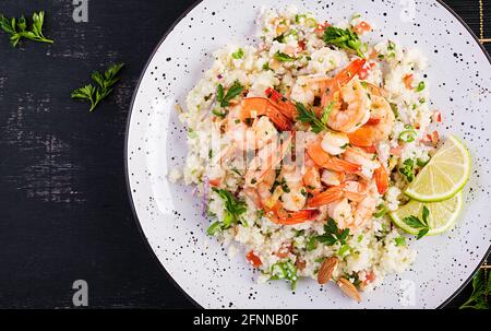 Couscous mit gerösteten Garnelen, Tomaten, roten Zwiebeln, Mandelnüssen und Petersilie. Marokkanisches Essen mit Couscous und Garnelen. Draufsicht, flach liegend Stockfoto