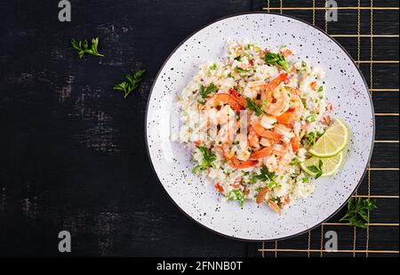 Couscous mit gerösteten Garnelen, Tomaten, roten Zwiebeln, Mandelnüssen und Petersilie. Marokkanisches Essen mit Couscous und Garnelen. Draufsicht, flach liegend Stockfoto