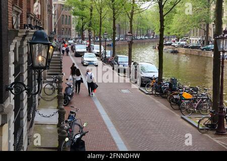AMSTERDAM, NIEDERLANDE - 10. JULI 2017: Menschen schlendern entlang des Herengracht-Kanals in Amsterdam. Amsterdam ist die Hauptstadt des Netzes Stockfoto
