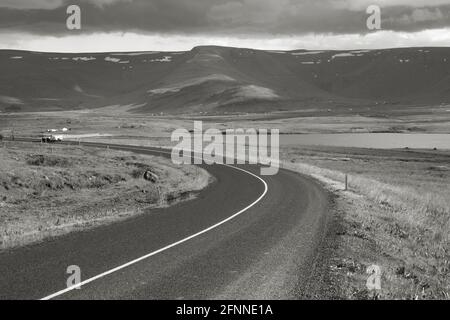 Straßenkurve neben dem Fjord Hvalfjordur in Island. Schwarzweiß-Monochrom-Ton. Stockfoto