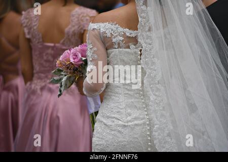 Die Braut trägt ein Hochzeitskleid mit Vintage-Spitze und Perlmutt-Knöpfen, einen transparenten Schleier und einen Brautstrauß in San Miguel de Allende, Mexiko. Stockfoto