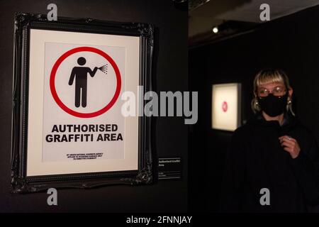 London, Großbritannien. 18 Mai 2021. Ein Besucher besucht die 'Authorized Graffiti Area', 2005, von Banksy. Vorschau von „The Art of Banksy“ bei Seven Dials, Covent Garden. Mehr als 100 Werke von Banksy sind aus privaten Sammlungen auf der ganzen Welt zu sehen und es ist das erste Mal, dass die weltweit größte Wanderausstellung authentischer Banksy-Kunstwerke nach Großbritannien kommt. Aufgrund der Coronavirus-Pandemie von 2020 verschoben, aber jetzt eröffnet, da die Sperrbeschränkungen gelockert werden. Die Show läuft vom 20. Mai bis zum 21. November 2021. Kredit: Stephen Chung / Alamy Live Nachrichten Stockfoto