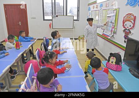 Nanning, China. Mai 2021. (210518) -- NANNING, 18. Mai 2021 (Xinhua) -- Pan Jiping lehrt Kinder im Dorf Xiaozhai der Gemeinde Longji, Bezirk Longsheng, südchinesische Autonome Region Guangxi Zhuang, die Hand-Maul-Krankheit zu verhindern, 18. Mai 2021. In Xiaozhai, einem Dorf am Fuße des Berges Fupingbao auf über 1,900 Metern Höhe, ist Pan Jiping seit mehr als 30 Jahren Landarzt hier. Pan, 57, gehört zu den Menschen in Hongyao, einem Zweig der Yao-Volksgruppe. Stockfoto