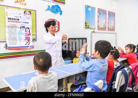 Nanning, China. Mai 2021. (210518) -- NANNING, 18. Mai 2021 (Xinhua) -- Pan Jiping lehrt Kinder, sich im Dorf Xiaozhai der Gemeinde Longji, Bezirk Longsheng, südchinesische Autonome Region Guangxi Zhuang, die Hände richtig zu waschen, 18. Mai 2021. In Xiaozhai, einem Dorf am Fuße des Berges Fupingbao auf über 1,900 Metern Höhe, ist Pan Jiping seit mehr als 30 Jahren Landarzt hier. Pan, 57, gehört zu den Menschen in Hongyao, einem Zweig der Yao-Volksgruppe. Stockfoto