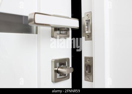 Moderner, moderner Satingriff. Moderne weiße Tür mit verchromtem Metallgriff. Stockfoto