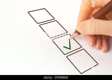 Hand hält schwarzen Stift und Kontrollkästchen ankreuzen. Person, die einen Checkbo einführt Stockfoto