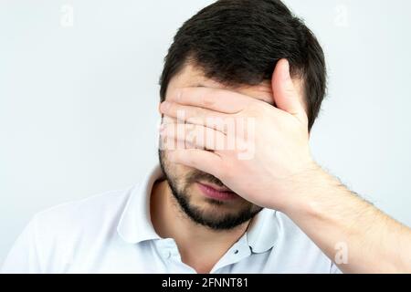 Nahaufnahme eines bärtigen Mannes, der eine Handfläche über seine hält Gesicht Stockfoto
