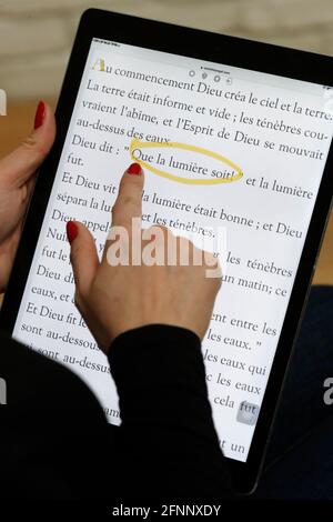 Frau liest und studiert die Evangelien der bibel auf einem digitalen iPad. Frankreich. Stockfoto