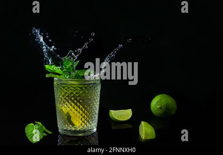 Frischer Sommer Mojito Cocktail mit Spritzer isoliert auf dunklem Hintergrund. Party Rum erfrischendes Getränk mit frischen Limetten und Minze. Stockfoto