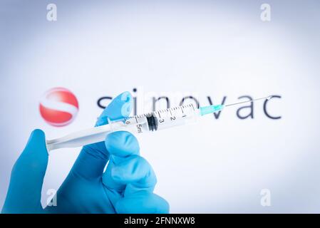 Am 18. Mai 2021 hält eine Hand eine Spritze vor dem Sinovac-Impfstofflogo in Barcelona, Spanien. Sinovac Biotech Ltd ist ein chinesisches Pharmaunternehmen Stockfoto